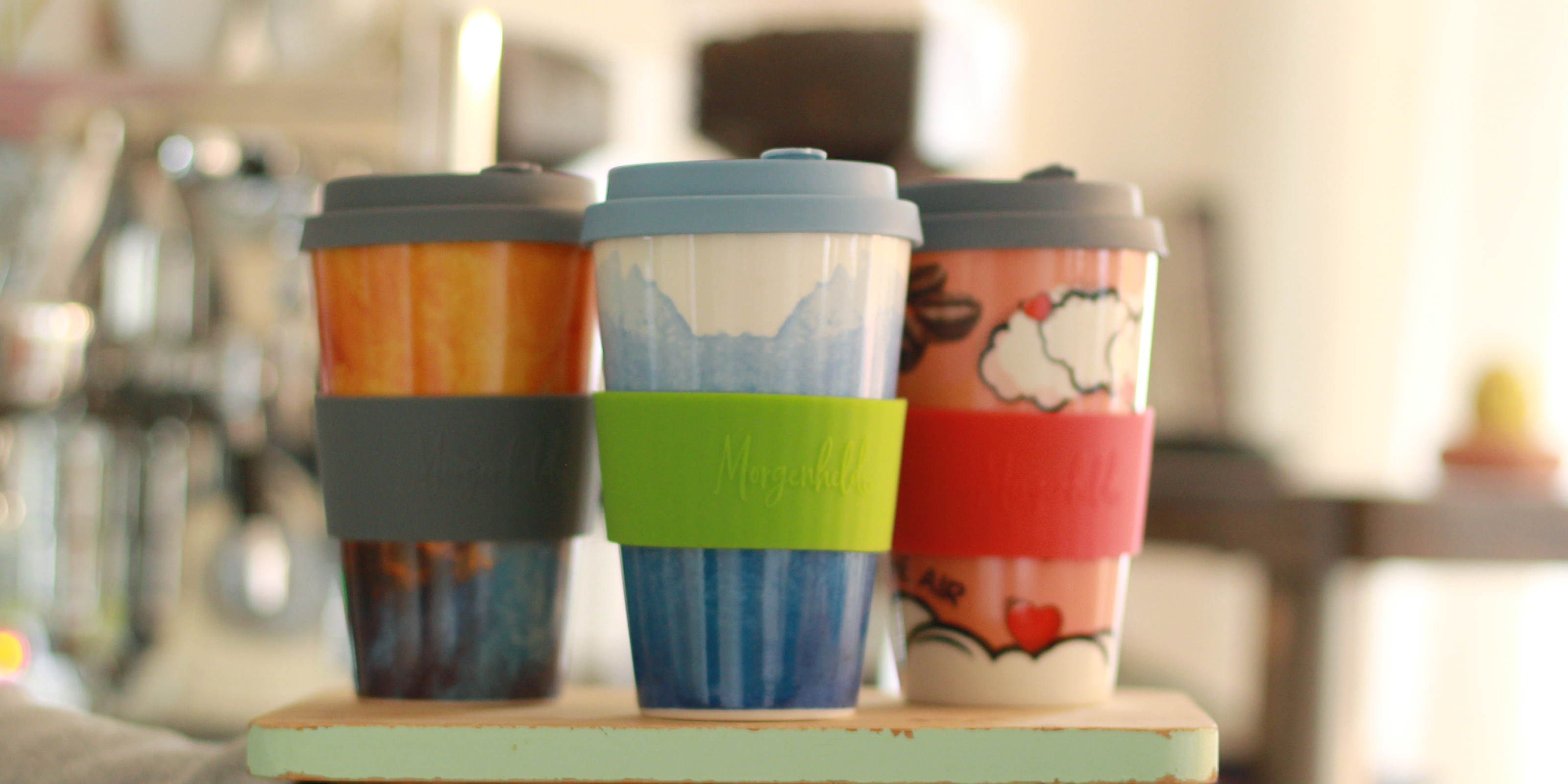 3 Morgenheld to Go Becher in farbenfrohen Designs auf einem Tablett
